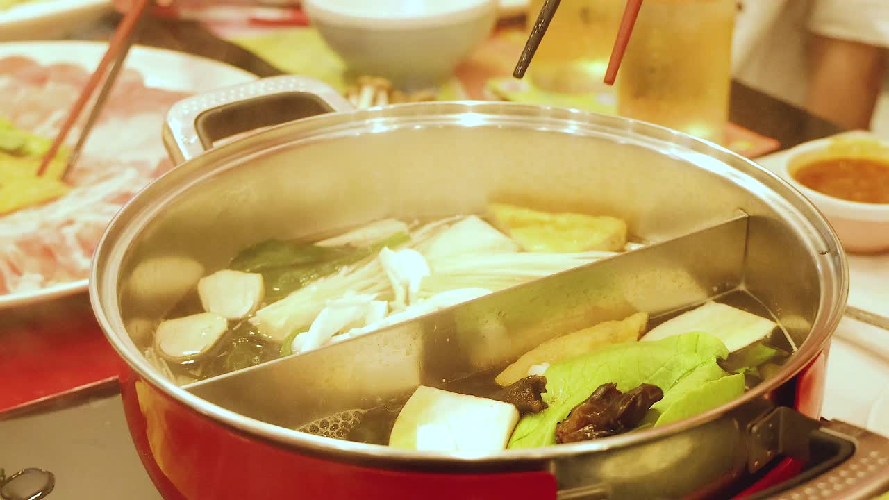 Chopsticks stirring ingredients in a hotpot