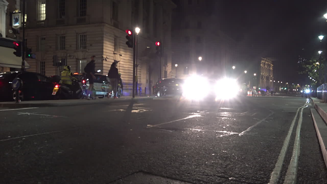 UK November 2018 - Police officers on motorcycles drive off and merge into traffic on a road at night time.