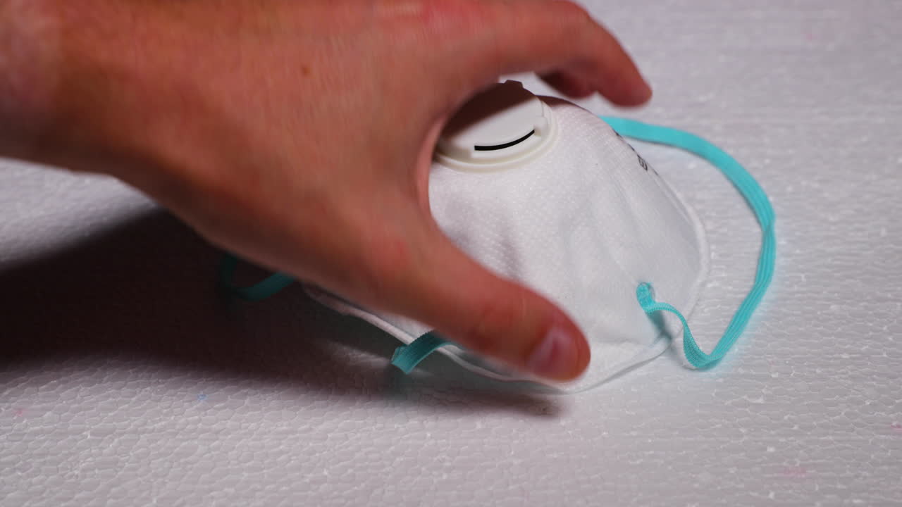 Men's Hand Laying Protective Facial White Mask Mask FFP2 Against Threats Like Corona Covid19 Virus Protects Mouth and Nose from Dark Black Board capture in 4k 60fps