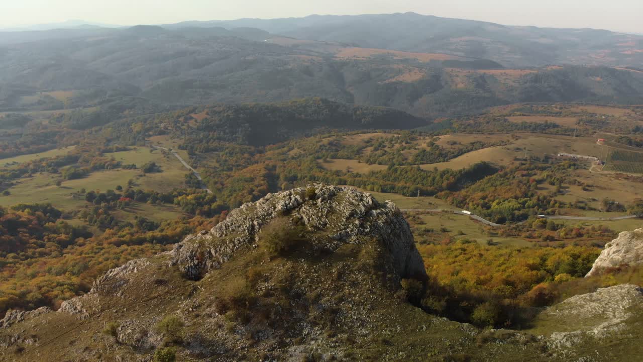 toma aérea de seguimiento sobre una colina rocosa, un valle y un bosque como fondo-1