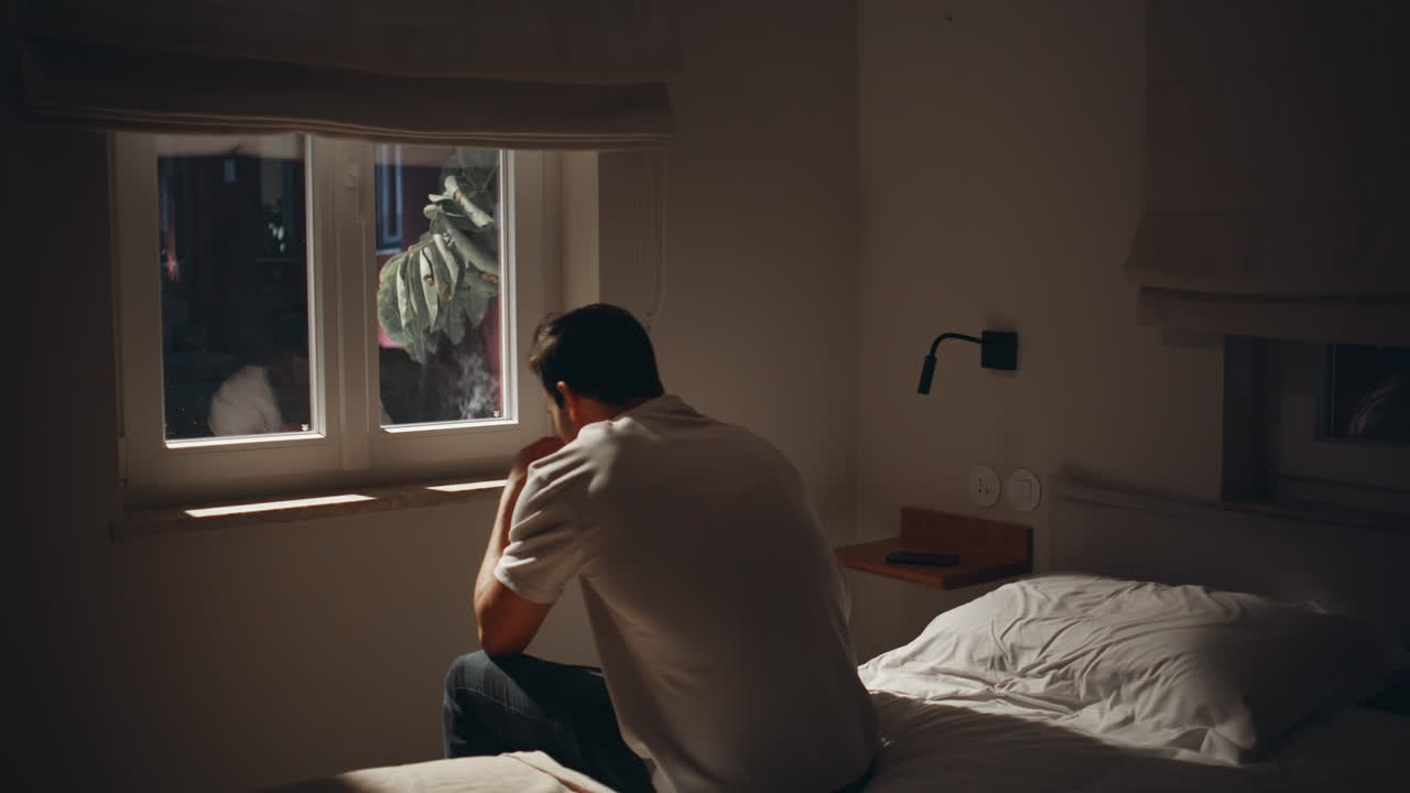 Man sitting sorrowfully bed at window moonlight. Male suffering sleep problem