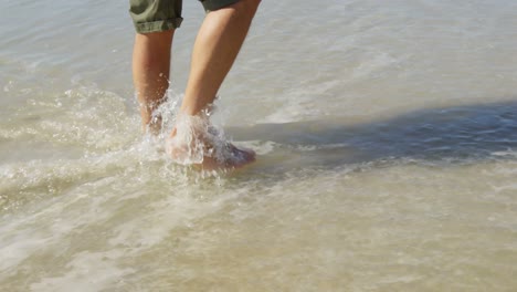 man walking in water at beach on a sunny day 4k