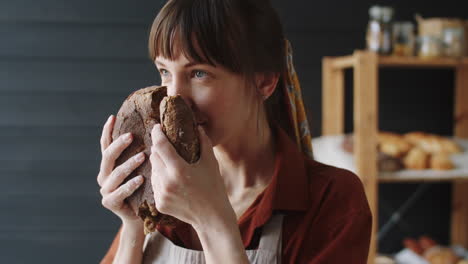 female baker enjoying smell of freshly baked rye bread