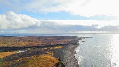 larga costa rocosa de la playa de islandia con hermosos acantilados junto al mar durante el día nublado con luz solar brillante