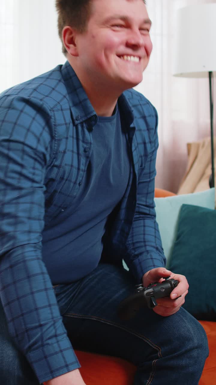 Man using joystick controller playing console online video game fun enjoying sitting on home sofa