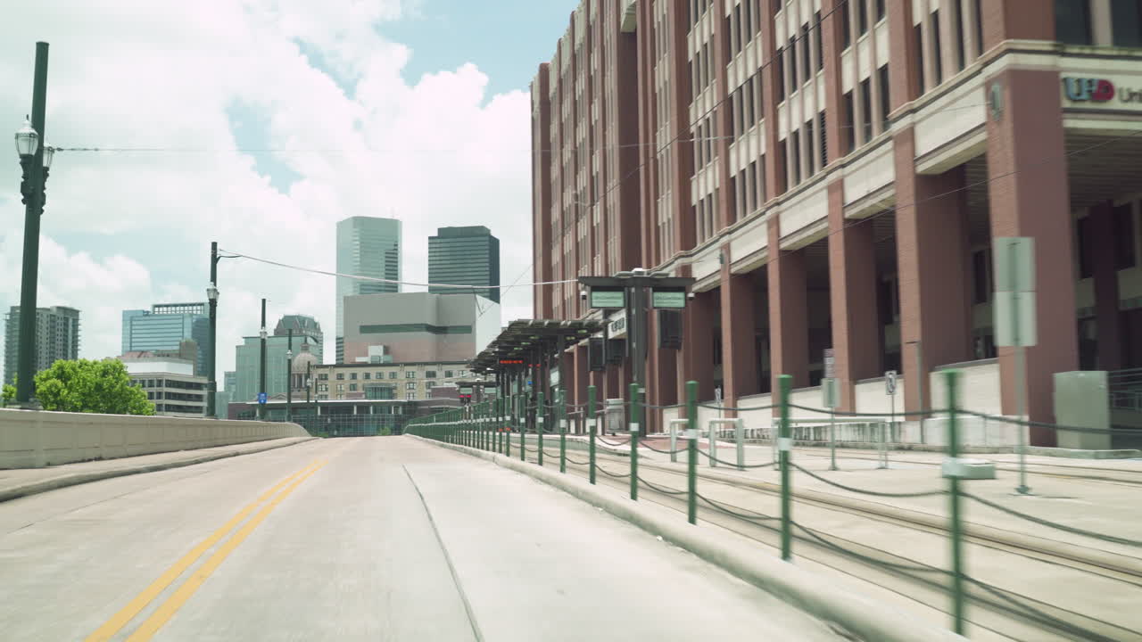 Driving Through Downtown Houston Main Street Passing University of Houston Downtown. Drive under a bride on Main Street inbound Houston Downtown Area in a sunny day, passing a Metro rail station