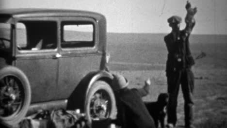 1934: man holding up hunted dead bird beside model a car.