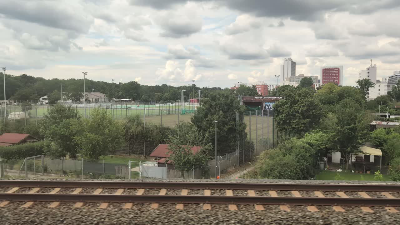 Train driving past German suburban areas with sports fields