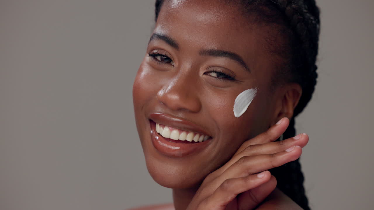 Young woman applying face cream and smiling