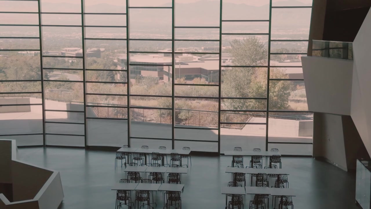 Right-to-left glide looks down at empty dining tables and a large window wall.