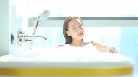 완벽한 피부를 가진 매우 매력적인 여성은 거품 목욕에서 목이 높습니다.