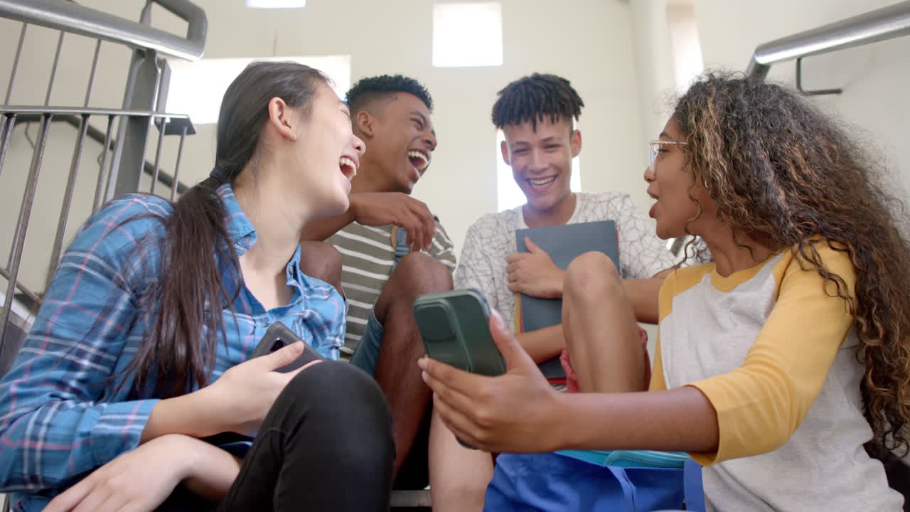 Diverse teenagers share a laugh on high school stairs