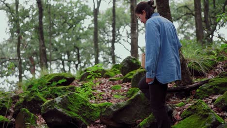 mujer con cesta caminando a través de piedras en el bosque