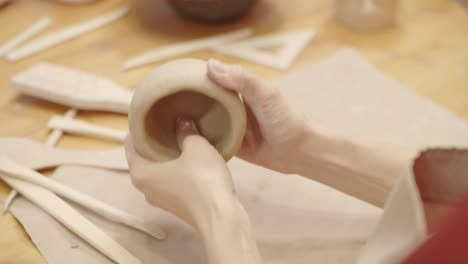 hands of anonymous female potter forming handmade clay vessel