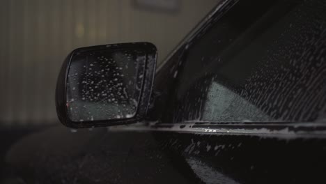 Car-side-view-mirror-with-shampoo-and-foam-after-car-wash,-closeup-shot