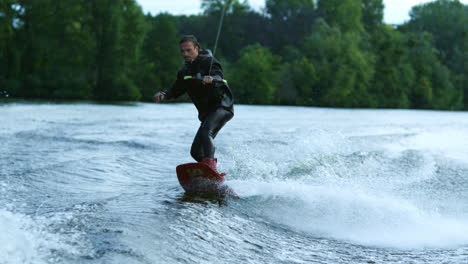 young man wakeboarding on river wave