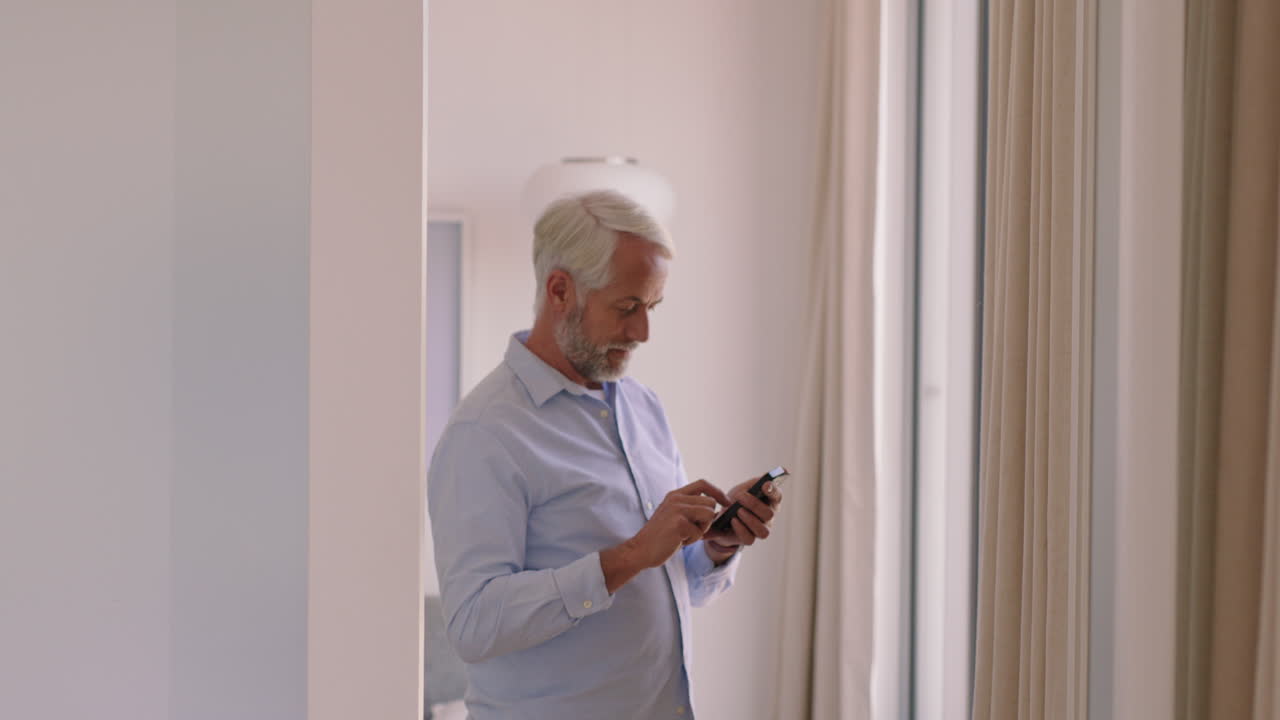 mature man using smartphone at home texting sharing messages on social media enjoying mobile phone communication