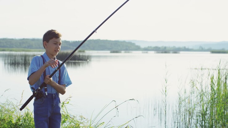Teen boy fishing on the lake and catching a fish with the rod
