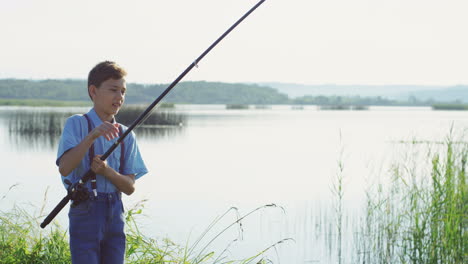 teenie-junge, der auf dem see fischt und mit der rute einen fisch fängt