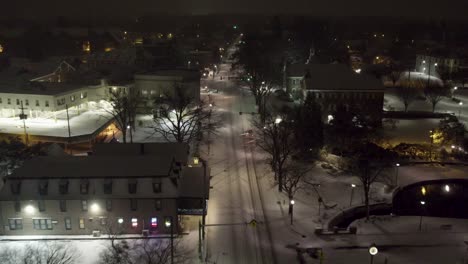 aerial shot following a car above a snowy road in downtown lititz at night, going south