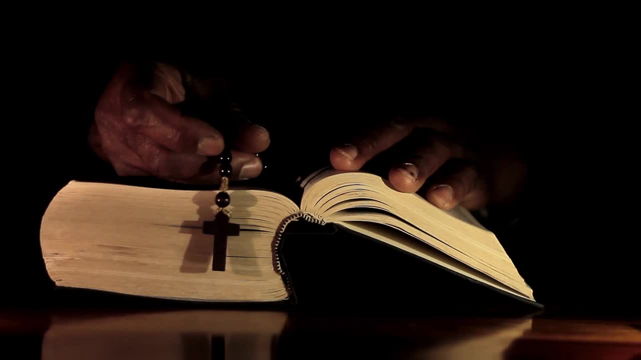 성경과 함께 손으로 신에게 기도하는 남자 검은 배경으로 기도하는 캐리비안 남자 스톡 비디오