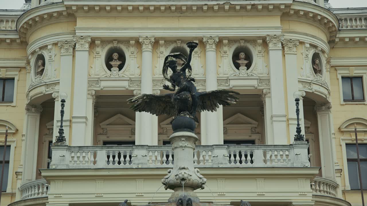 Sculptural fountain with a winged figure in front of a grand historic building in Bratislava