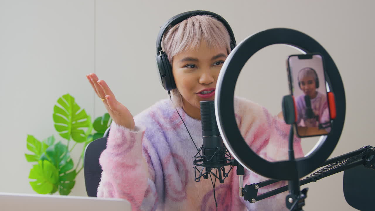 vlogger femenina con auriculares con micrófono transmitiendo en vivo en el teléfono móvil
