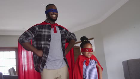 happy african american father and daughter having fun, wearing superhero costumes