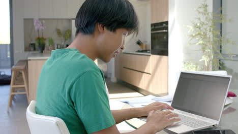 teenage asian boy focused on his laptop at home