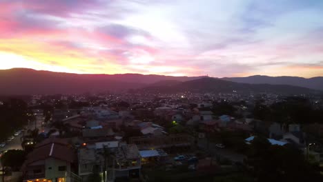 aerial view of a city with small buildings, mountains and beach at sunset. drone footage.
