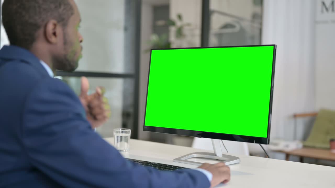 Afrikansk forretningsmand bruger en stationær computer med grøn Chroma Key-skærm.