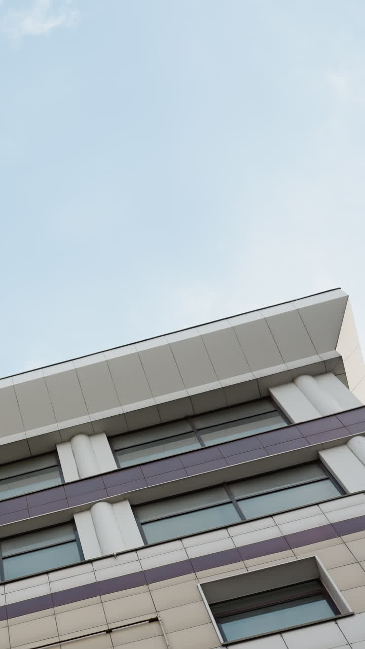 vista rotativa cercana de un edificio de la ciudad moderna con una fachada de vidrio elegante, destacando sus detalles arquitectónicos, con la perspectiva contra un cielo azul claro