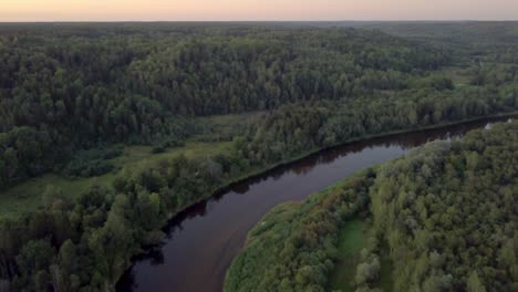 Hermoso-Y-Exuberante-Bosque-Verde-Entre-Un-Río-Floreciente-En-Letonia-Durante-Un-Majestuoso-Amanecer---Toma-Aérea