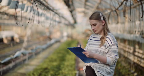 Female-Gardener-Examining-Plants-At-Greenhouse-10