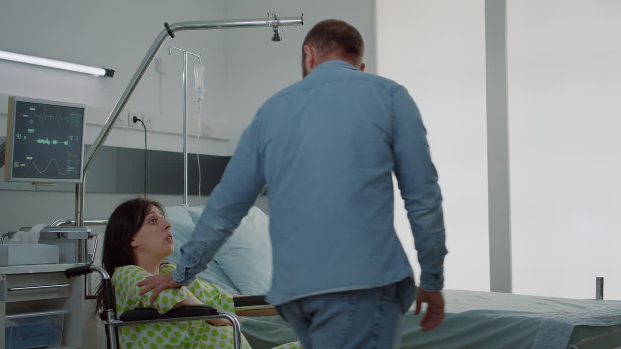 Young father supporting pregnant wife from wheelchair