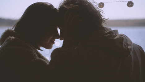 a young couple in love put their heads together in the back of a caravan by a lake