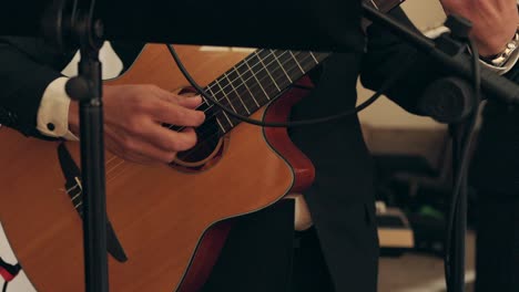 man strumming acoustic guitar during formal indoor event or performance