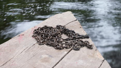 una cadena oxidada en la parte delantera de un barco de madera que viaja por el río amazonas