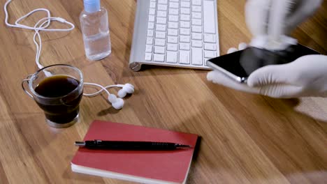 hands cleaning the smartphone with an alcohol hand sanitizer and cleaning with cloth