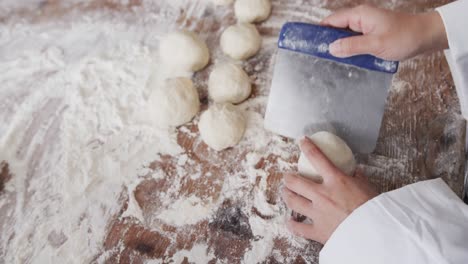 Asian-female-baker-working-in-bakery-kitchen,-making-rolls-from-dough-in-slow-motion