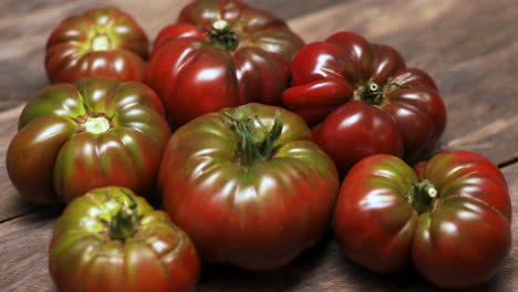 cherokee purple homegrown tomatoes on wooden table close up panning shot across the fruit