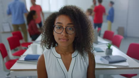 Close-up-view-of-smiling-afro-businesswoman-posing-in-modern-office