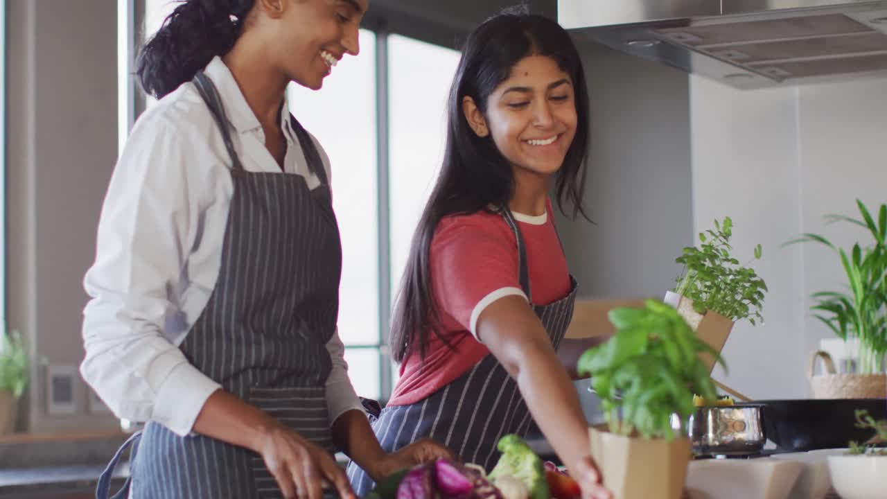 Video de amigas diversas y felices cortando verduras y preparando comida