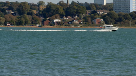 motor yacht goes fast through the frame at the solent southampton with weston in background