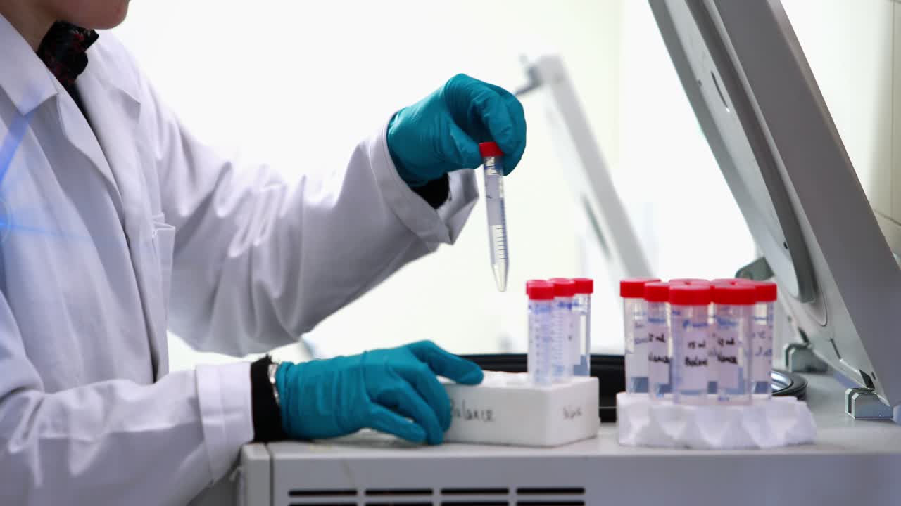 Blue spot of light against mid section of caucasian female scientist putting test-tubes in a machine