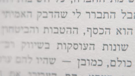 a macro smooth and detailed pan right shot of a book in hebrew, black letters on white paper, 4k video