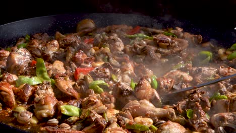 Cook-moving-the-meat-of-the-paella-with-the-shovel