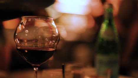 a wine glass fills with red wine in a softly lit, cozy environment, capturing a moment of relaxation and indulgence