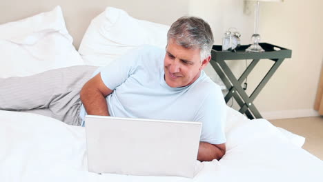 Hombre-Con-Laptop-Acostado-En-Su-Cama