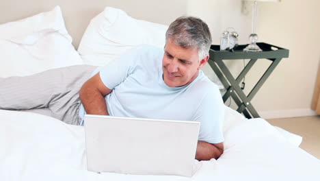 hombre con laptop tendido en su cama